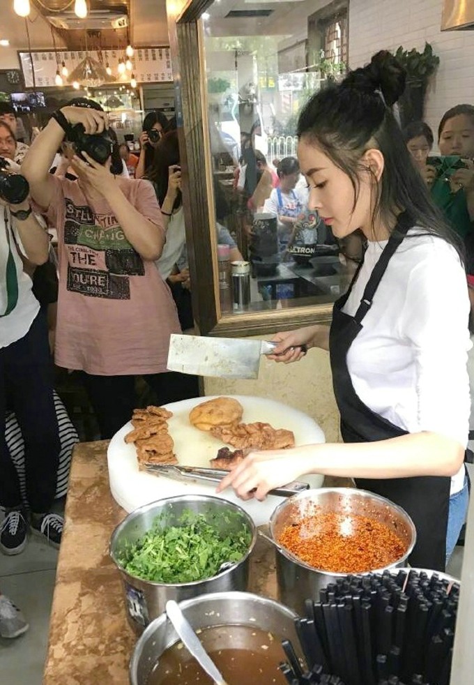 张天爱化身市井烟火中的卤煮西施 暖黄灯光下,张天爱托腮凝望,与背景里丰盛的卤煮食材构成一幅温馨画面